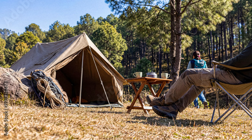 Two people enjoying a relaxing camping trip in a peaceful forest, with a classic tent setup.