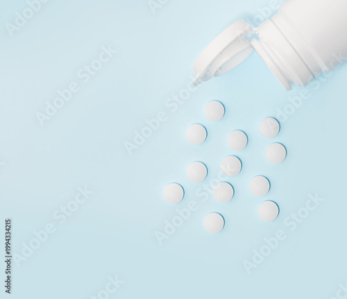 Medicine pills capsule spilling out of jar on blue background. Ideal for healthcare, pharmaceutical treatments, and medical medication industries.