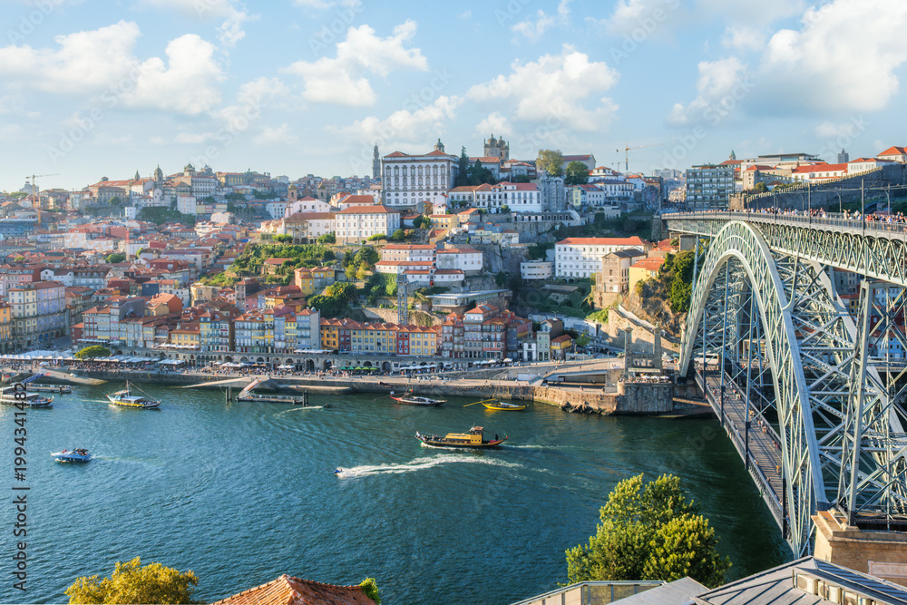 Obraz premium High angle view of the Dom Luis I bridge and the Douro river with several boats and the Ribeira district Porto Portugal.