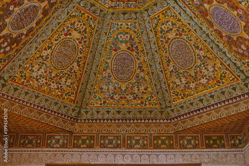 Lavishly ornate wooden ceiling painted in colorful floral motifs in a room adjoining the Small Riad garden E side, Bahia Palace. Marrakesh-Morocco-270