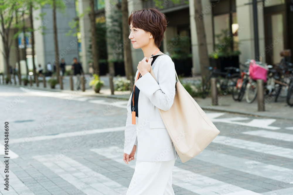 Fototapeta premium 新緑の並木道を歩く30代ビジネス女性