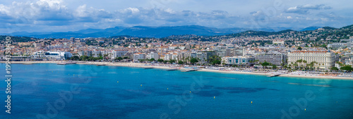 A wide aerial view shows the Cannes waterfront in France, the Bay of Cannes, the Palais des Festivals et des Congres, and Carlton Cannes along the Croisette.