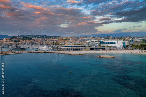 фотографія Aerial view of Cannes, France shows the Bay of Cannes, sandy beach, Vieux Port yachts, yellow buoys, and the Palais des Festivals, with terraced city and hills in sun
