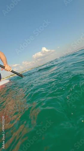 Action camera dives into water waves of blue summer sea shoot man on paddleboard. Sup board. Travel vacation holiday. Vertical shot