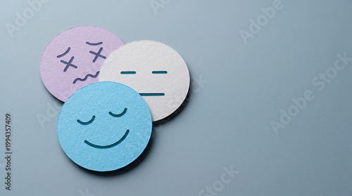 Three overlapping paper-cut emotion circles — blue happy, white neutral, purple stressed — arranged on a calm steel-blue background.