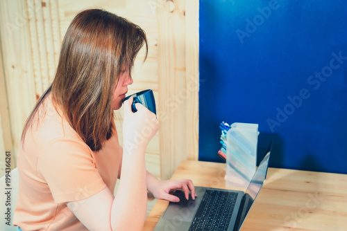 asian woman in casual wear drink coffee and work from home on her bedroom for protect corona or covid-19 virus