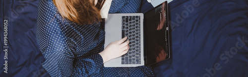 asian woman in classic blue pajama cloth work from home and sit on her bed for protect corona or covid-19 virus
