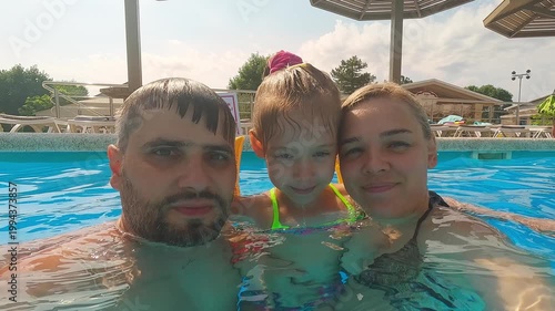 Portrait of happy family look at camera and smile swimming in blue hotel pool. Summer vacation holiday travel
