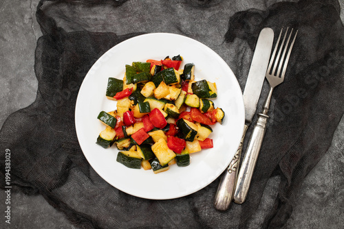 Roasted vegetables mix on white dish. Top view