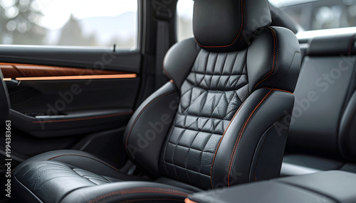 A close-up shot showcases the luxurious interior of a modern car, highlighting the intricately stitched black leather seats with vibrant orange detailing against a blurred natural backdrop.
