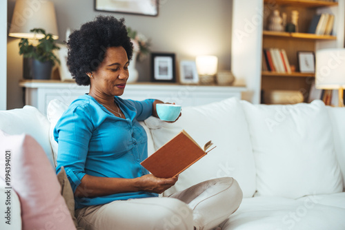 Woman Sipping Coffee and Reading a Book on Cozy Couch at Home