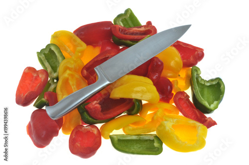 Poivrons, jaunes, rouges et verts coupés avec un couteau en gros plan isolés sur fond blanc