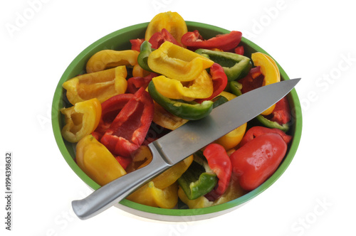 Poivrons, jaunes, rouges et verts coupés avec un couteau posés sur un plateau en gros plan isolé sur fond blanc