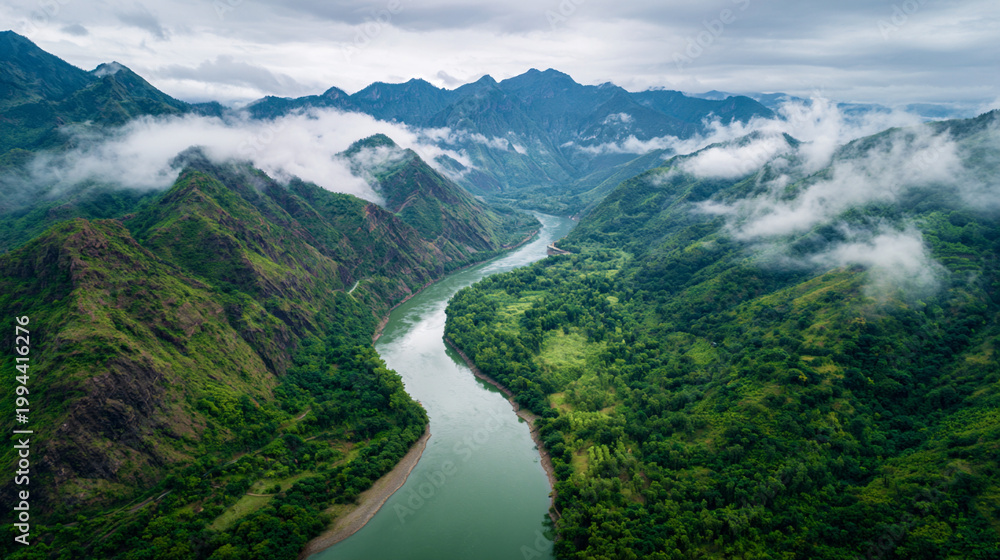 Naklejka premium aerial river bend through lush mountains, vertical perspective of winding river in green mountain valley, ultra distant aerial view of river meander and forested peaks