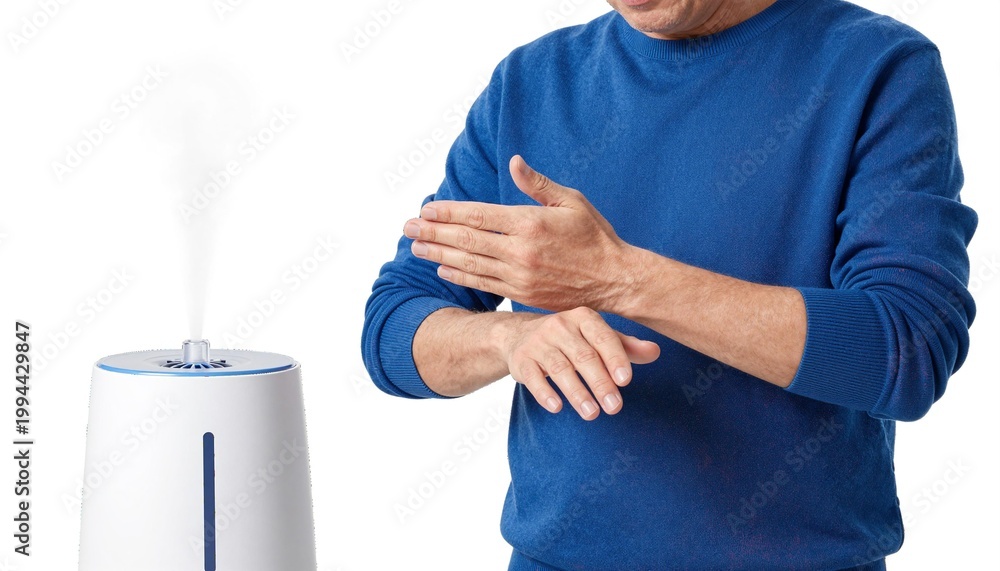 Fototapeta premium Man in blue sweater warming his hands near a white humidifier emitting cool mist