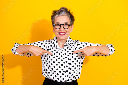 Tableau sur toile Confident mature businesswoman short grey hair glasses points to herself yellow