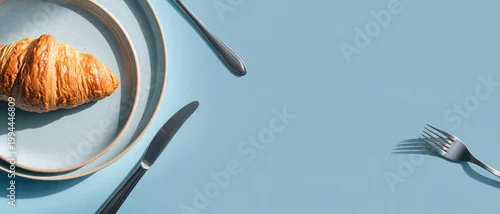 Obraz  z motywem Croissant on plate with cutlery flat lay on blue background with copy space for breakfast menu or food advertising banner.