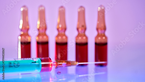 Vials and a syringe on a flat surface with a colorful background in a laboratory setting