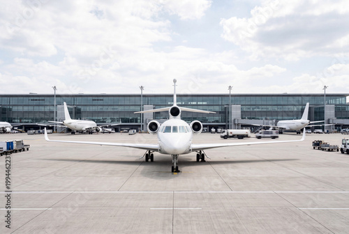 Private business jet parked on apron in front of terminal building