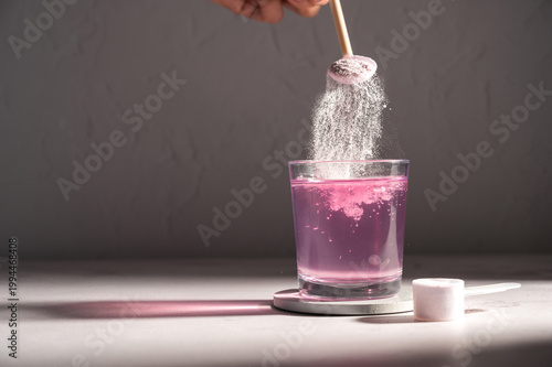Pouring food supplement powder in glass of water. Collagen, protein powder, vitamins.
