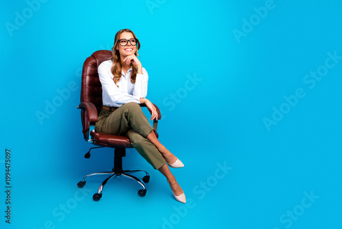 Schilderij op canvas Confident young businesswoman sitting in a leather office chair smiling against