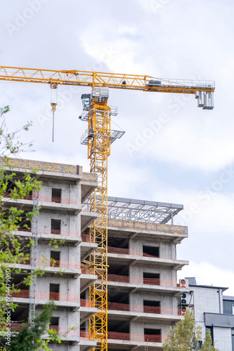 Konstfotografi A construction tower crane operates against the backdrop of an unfinished building and a blue sky