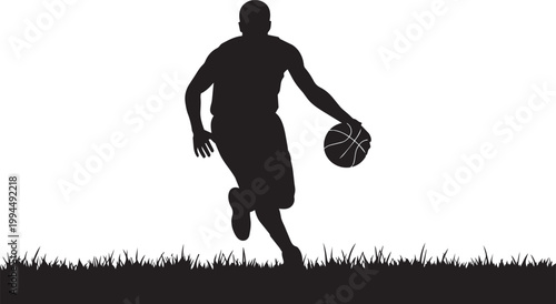 Silhouette of a basketball player dribbling a ball on a grassy field