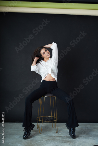 Young athletic slim energetic woman with dark long hair posing in the studio