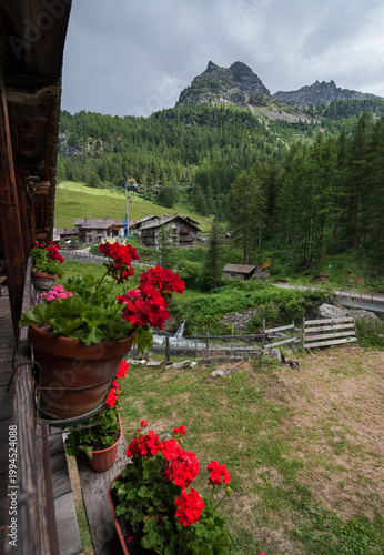 chalet balcony with pots of red geraniums, beautiful alpine mountain landscape
