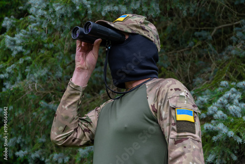 Fotografía Military scout with binoculars and Ukrainian flag patches
