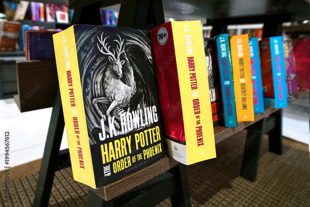 Fototapeta premium Minsk, Belarus. Apr 12, 2026. Row of colorful Harry Potter fantasy novels published by bloomsbury arranged on wooden display stand inside retail book shop with blurred white bookshelves in background