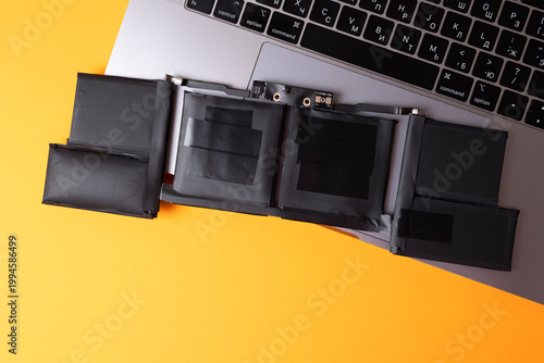 Modern Laptop Battery Repair Setup. Removable Battery Cell Pack On color Desk With Keyboard