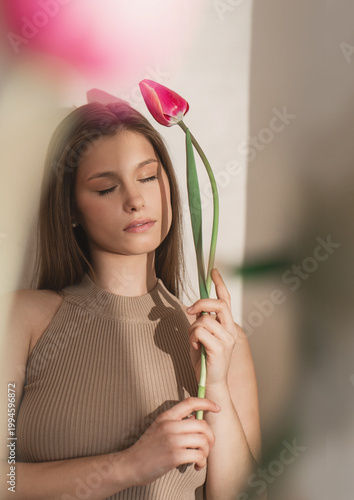 Quadro su tela artistic female portrait with closed eyes holding single tulip soft light natura