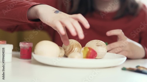Little girl painting Easter eggs at home, 4K 10-bit cinematic footage of child decorating colorful eggs with watercolor brush for spring holiday, authentic lifestyle.
