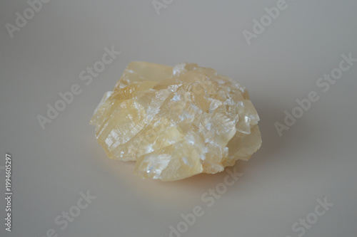Quadro em tela Natural raw yellow calcite crystal mineral specimen with translucent crystalline layers on a neutral grey background for geology and alternative healing concepts