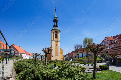 Church stands tall in a small town square with clean streets and bright sky during the day. Srebrna Góra, Poland.
