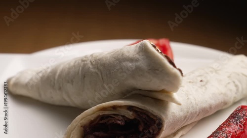 Traditional Turkish meat doner kebab wraps rotating with tomato and grilled pepper on a white plate, fa01