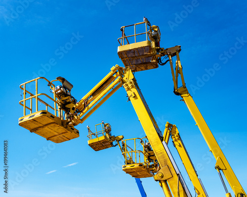 Cherry pickers on a blue sky background