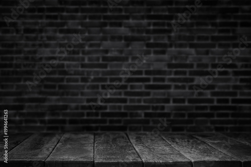 Dark blurred brick wall background with wooden table surface in front. Industrial loft style scene suitable for product presentation, mockups and design use