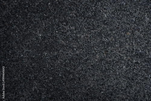 Dark asphalt or concrete surface with small stones and rough grain texture. Natural abstract background with subtle variation and industrial feel, suitable for design, overlays and construction themes