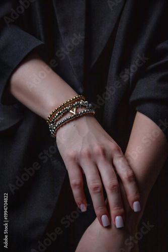 Sophisticated wrist jewelry, neat manicure, black suit detail, fashion shot