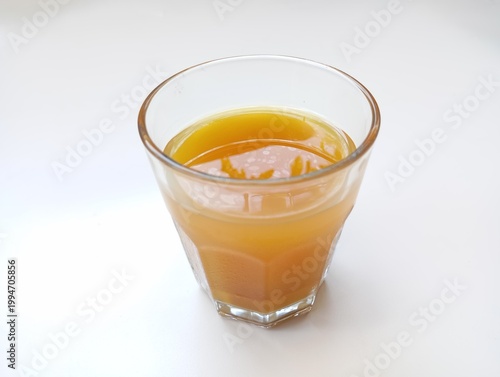 A glass of traditional herbal turmeric drink or orange juice isolated on white background. Healthy lifestyle.