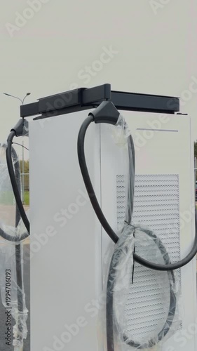 Electric station details. Electric vehicle charger with dual nozzles and cables. Minimalist focused image showcasing dual nozzles and textured metal connectors on electric car charger
