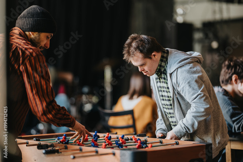 Fotografie A group of students play foosball at a tabletop game in a relaxed indoor space