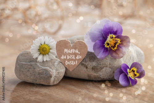 Mother's Day - Greeting card with German text for Mom, you're the best - Decorative heart with blossoms and stones on wood - bokeh - background with light and ornaments