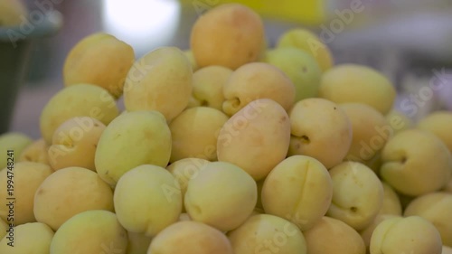 A close-up of fresh apricots displayed at a market, showcasing their vibrant yellow color and natural texture.