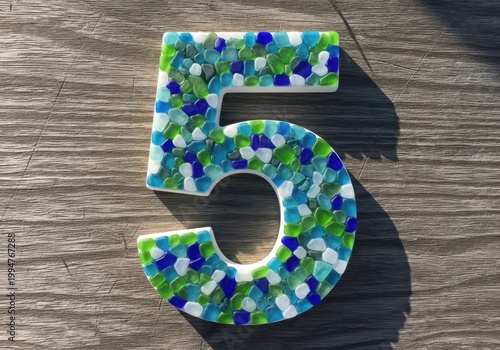 Colorful mosaic number five on a textured surface