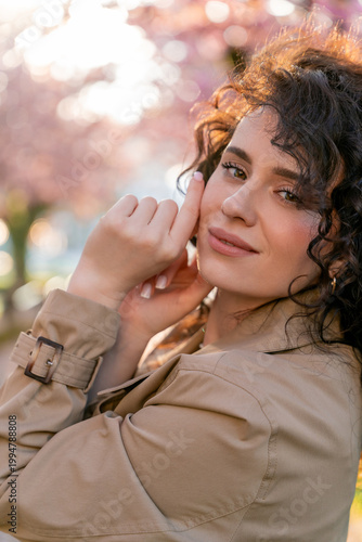 Closeup Portrait of young woman near blooming pink sakura. Spring. Unity with nature.
