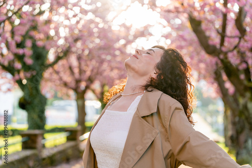 Closeup Portrait of young woman near blooming pink sakura. Spring. Unity with nature.