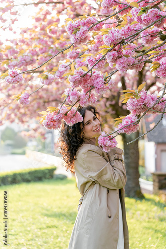 Young woman resting near blooming pink sakura. Spring. Unity with nature.